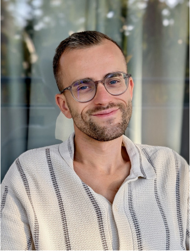 Quentin Kuntzmann, product designer, photographié devant une façade vitrée.